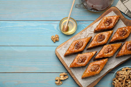 Delicious sweet baklava with walnuts and honey on turquoise wooden table, flat lay. Space for textの写真素材