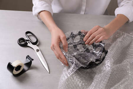Woman covering ceramic bowl with wrap at light gray table, closeupの写真素材