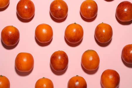 Many ripe sicilian oranges on pink background, flat lay