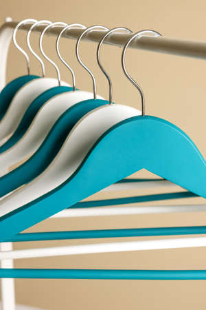 Clothes hangers on metal rail against beige background, closeup viewの写真素材