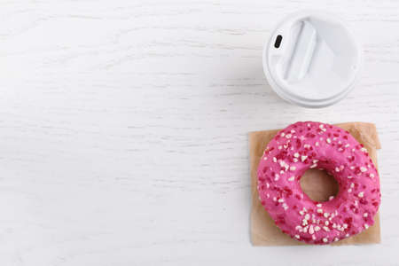 Tasty frosted donut and hot drink on white wooden table, flat lay. Space for textの写真素材