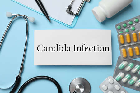Card with phrase Candida Infection, stethoscope, pills and clipboard on light blue background, flat...