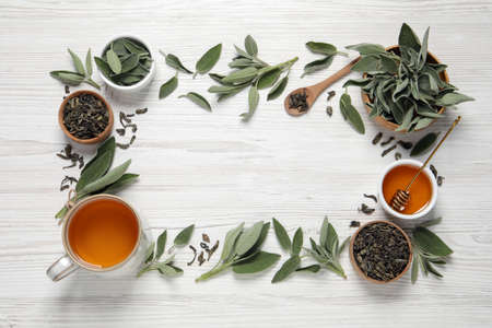 Flat lay composition with cup of sage tea and green leaves on white wooden table. Space for textの写真素材