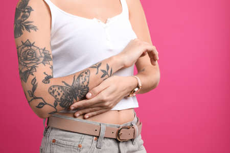 Beautiful woman with tattoos on arm against pink background, closeupの写真素材
