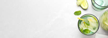 Refreshing water with cucumber, lemon and mint on white table, flat lay with space for text. banner designの写真素材