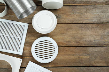 Parts of home ventilation system on wooden surface, flat lay. Space for text