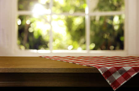 Red and white checkered tablecloth on wooden table indoors, space for design. bokeh effect