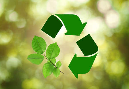 Recycling symbol made of arrows and branch with green leaves on blurred background. bokeh effect