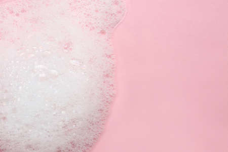 Fluffy bath foam on pink background, top view. Space for text