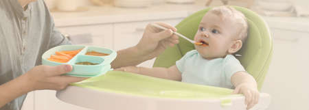 Father feeding his cute little baby in the kitchen. banner designの写真素材