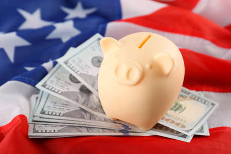Piggy bank and dollar banknotes on American flag, closeupの写真素材