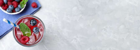 Delicious berry lemonade made with soda water on gray table, flat lay with space for text. banner...