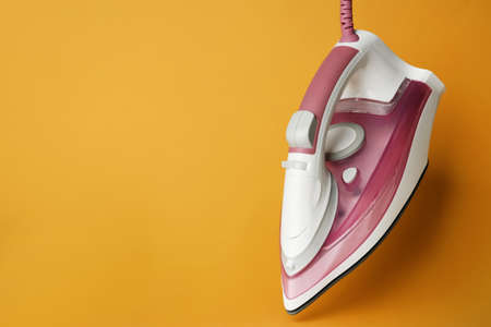 One modern iron on orange background, space for text. home appliancesの写真素材