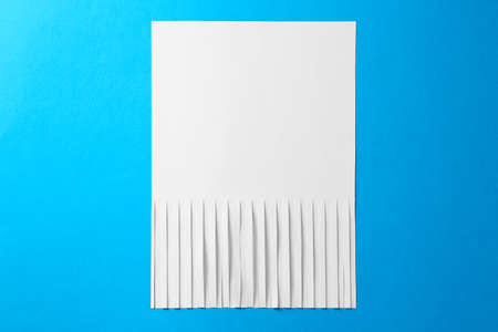 Half shredded sheet of paper on light blue background, top view