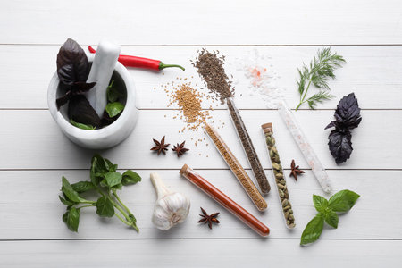 Flat lay composition with various spices, test tubes and fresh herbs on white wooden backgroundの写真素材