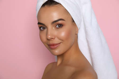 Beautiful young woman with towel on head against pink background