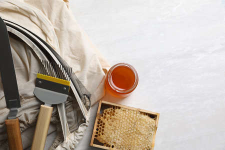 Different beekeeping tools and jar of honey on white table, flat lay. Space for textの写真素材