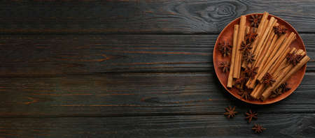 Aromatic cinnamon sticks and anise on black wooden table, flat lay with space for text. banner designの写真素材