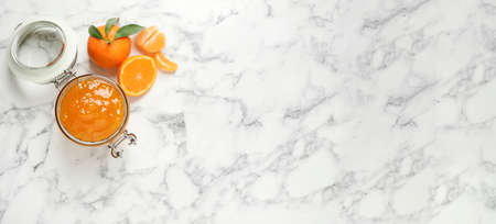 Flat lay composition with tasty tangerine jam on white marble table, space for text. banner designの写真素材