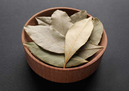 Bay leaves in wooden bowl on gray backgroundの写真素材