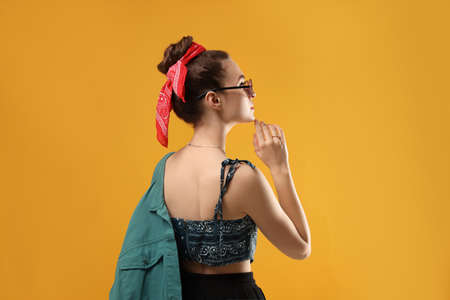 Woman with stylish bandana on yellow background