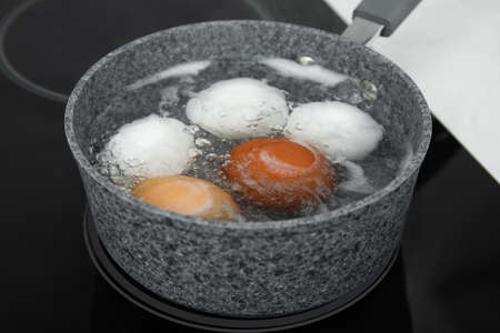 Boiling chicken eggs in saucepan on electric stoveの写真素材