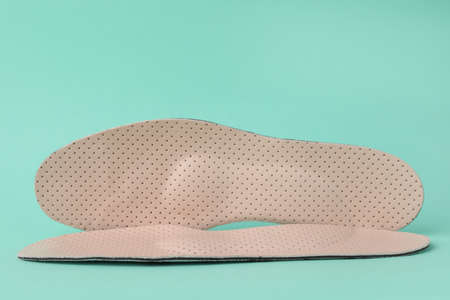 Beige comfortable orthopedic insoles on turquoise backgroundの写真素材