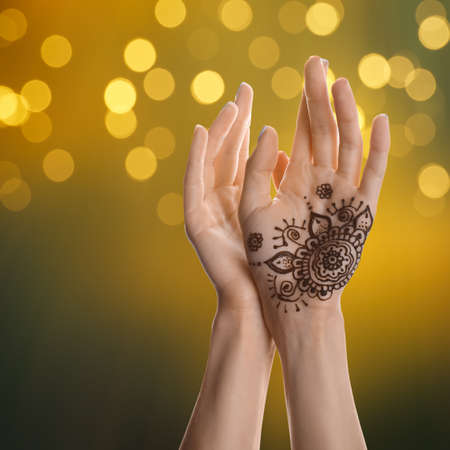 Woman with henna tattoo on palm against blurred lights, bokeh effectの写真素材