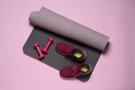 Exercise mat, dumbbells and shoes on pink background, flat layの写真素材