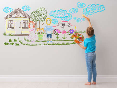 Cute child girl painting on light gray wall indoorsの写真素材