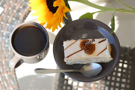 Tasty dessert, cup of fresh aromatic coffee and flower on glass table outdoors, above view