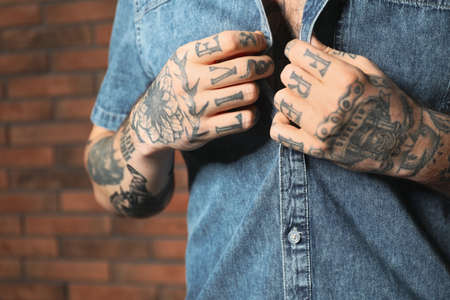 Young man with tattoos on body near brick wall, closeupの写真素材