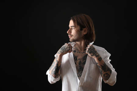 Young man with tattoos on body against black backgroundの写真素材