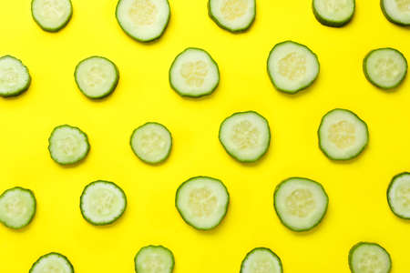 Slices of fresh ripe cucumber on yellow background, flat layの写真素材