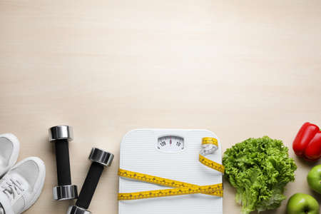 Flat lay composition with bathroom scale and measuring tape on wooden floor, space for text. weight loss conceptの写真素材