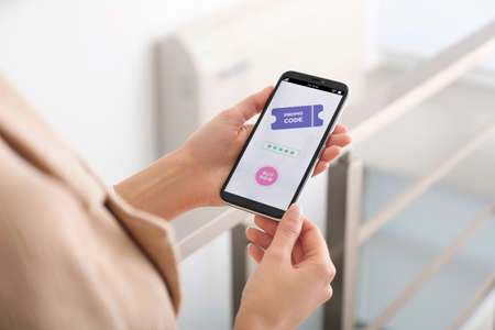 Woman holding smartphone with activated promo code in online shopping app indoors, closeup