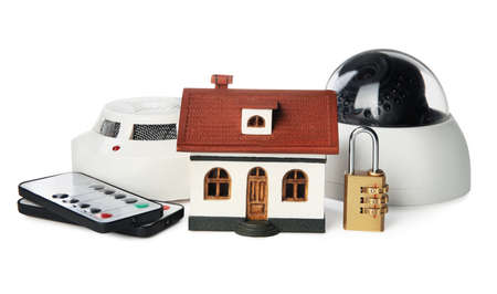 House model, CCTV camera, remote controls, lock and smoke detector on white background. home...