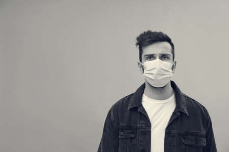 Man wearing medical face mask on light background, space for text. black and white photographyの写真素材