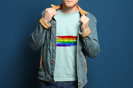 Young man wearing t-shirt with image of LGBT pride flag on blue backgroundの写真素材