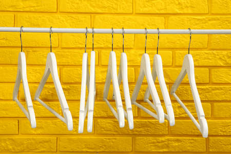 Wardrobe rack with many hangers near yellow brick wallの写真素材