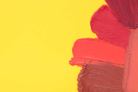Smears of different beautiful lipsticks on yellow background, top view. Space for textの写真素材