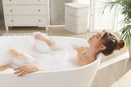 Beautiful woman enjoying bubble bath at home