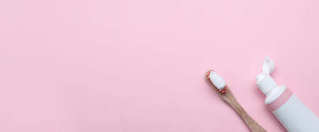 Tube and brush with toothpaste on light pink background, flat lay with space for text. banner design