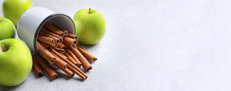 Fresh apples and mug with cinnamon sticks on table, space for text. banner design