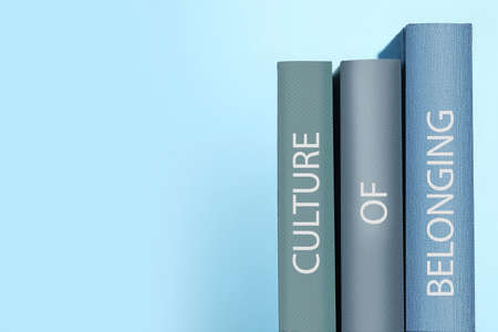 Books with phrase Culture of Belonging on light blue background, space for textの写真素材