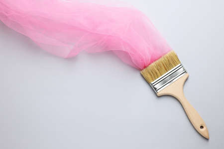 Brush painting with pink tulle on light background, top view. creative concept
