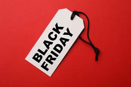 White tag with phrase BLACK FRIDAY on red background, top viewの写真素材