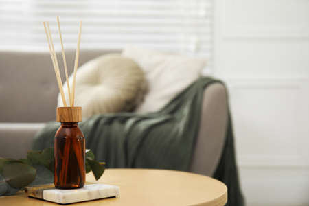 Reed diffuser with eucalyptus on wooden table in living room. Space for textの写真素材
