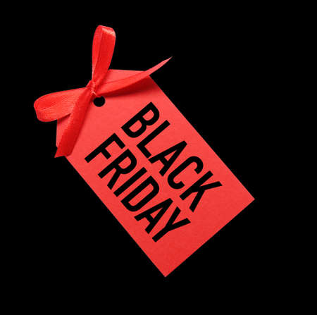 Red tag with phrase BLACK FRIDAY on dark background, top view