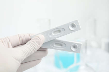 Doctor holding two disposable express tests for hepatitis indoors, closeup